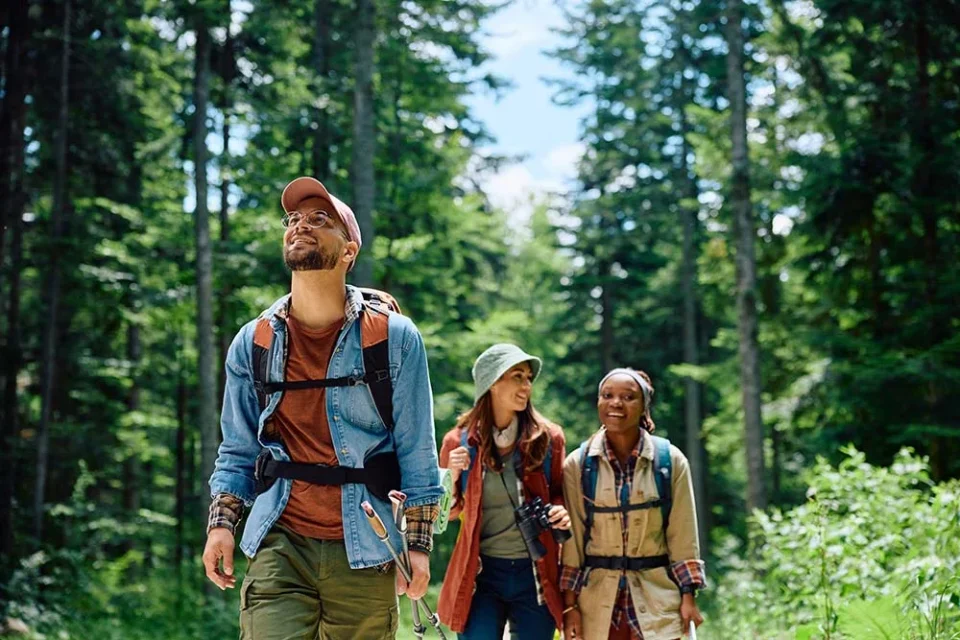 Happy backpacker and his friends hiking in forest